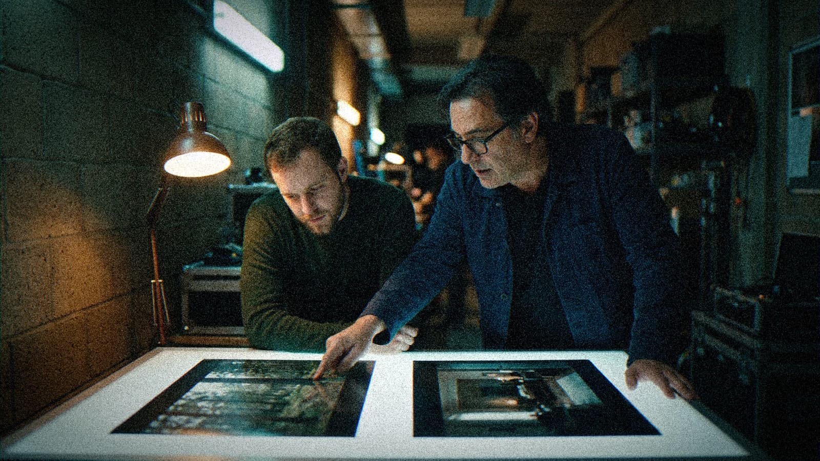 Deux producteurs comparant deux images sur une table lumineuse dans le couloir d'une boîte de production