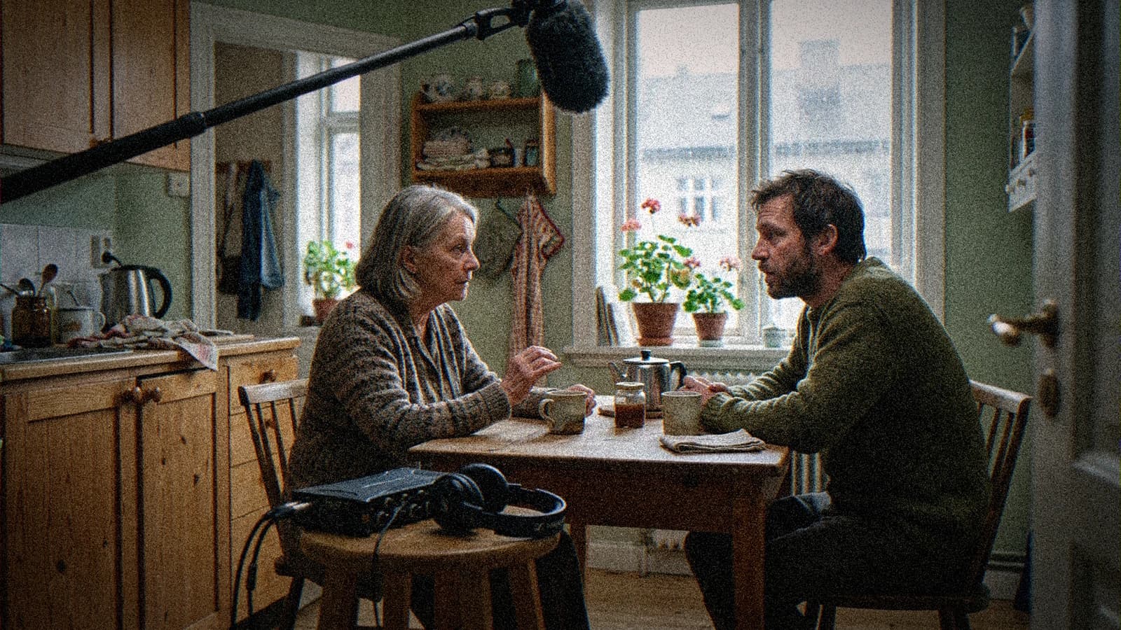 Deux comédiens en dialogue à une table de cuisine, perche son en haut du cadre, plan de dialogue confié à Veo