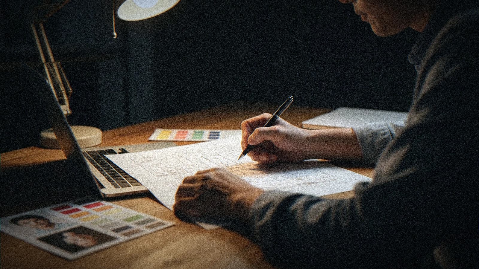 Director annotating a printed storyboard next to a laptop, physical references on the desk, human studio atmosphere